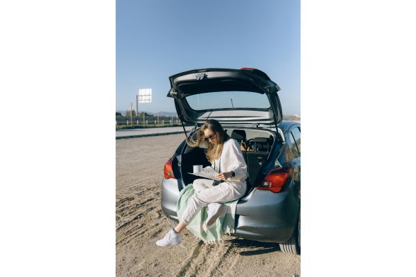 A woman sitting behind her hatchback 