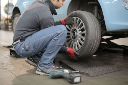 A man removing a wheel from a car 