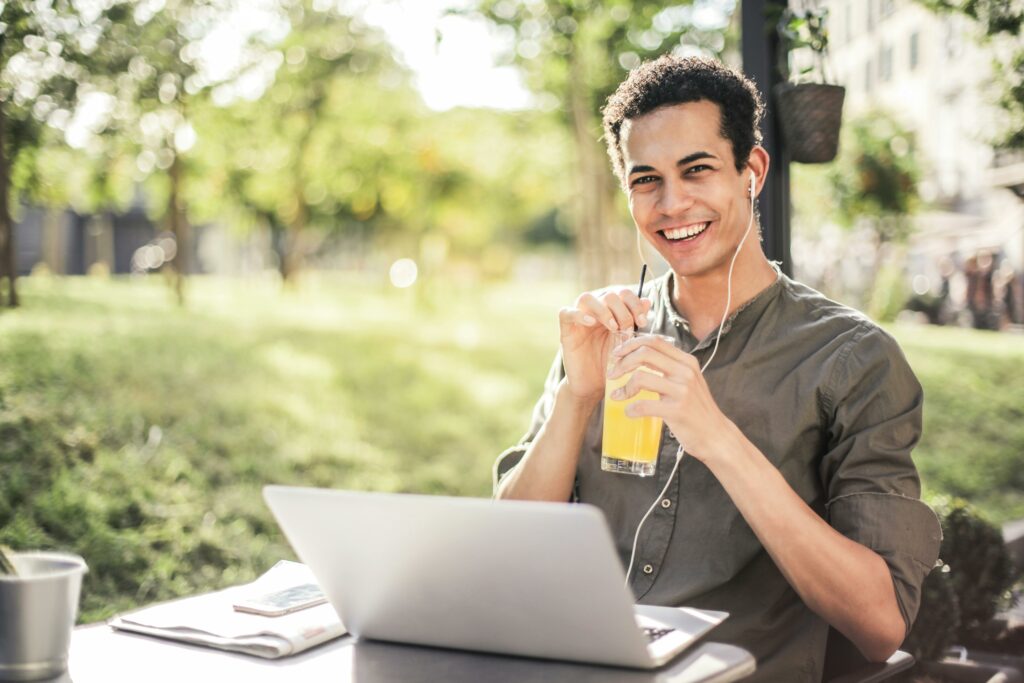 A man sitting outside with his laptop drinking a detox drink