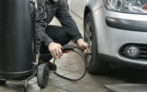 A man putting air in his car tire 