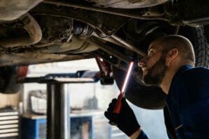 man inspecting under side of car 