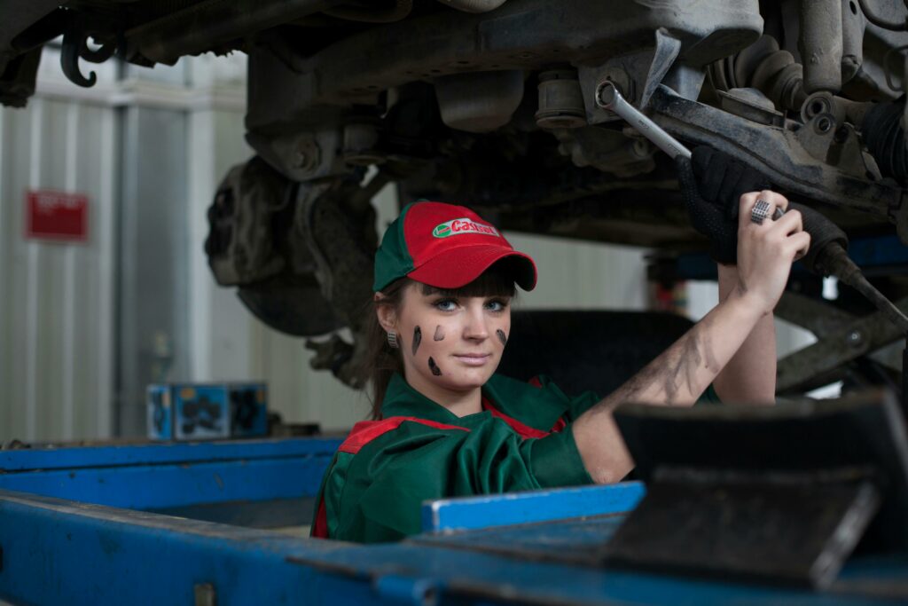 a girl under a car changing oil