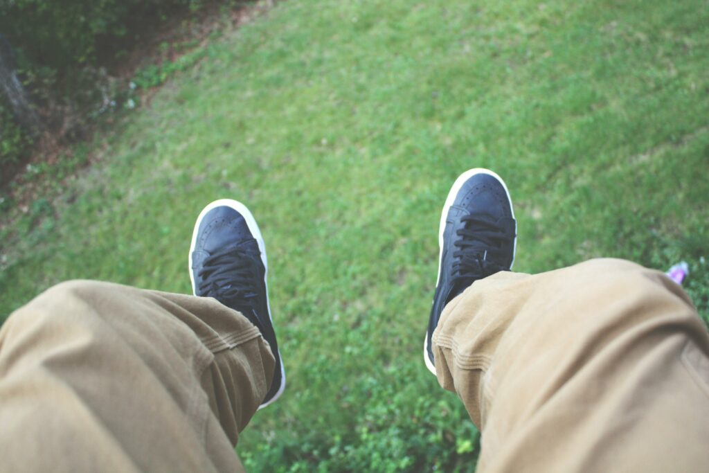 a person sitting on grass wearing chinos